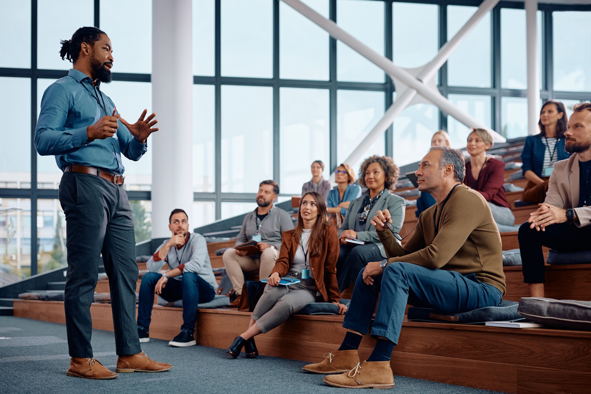 Black businessman talking to large group of entrepreneurs during an education event in conference hall.